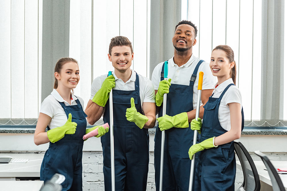 team of cleaners looking at camera and showing thumbs up