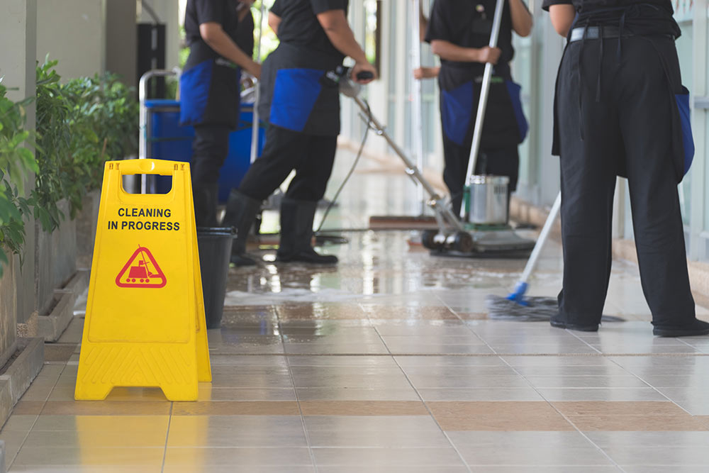 Cropped image of woman in protective gloves using a flat wet-mop and machine while cleaning floor